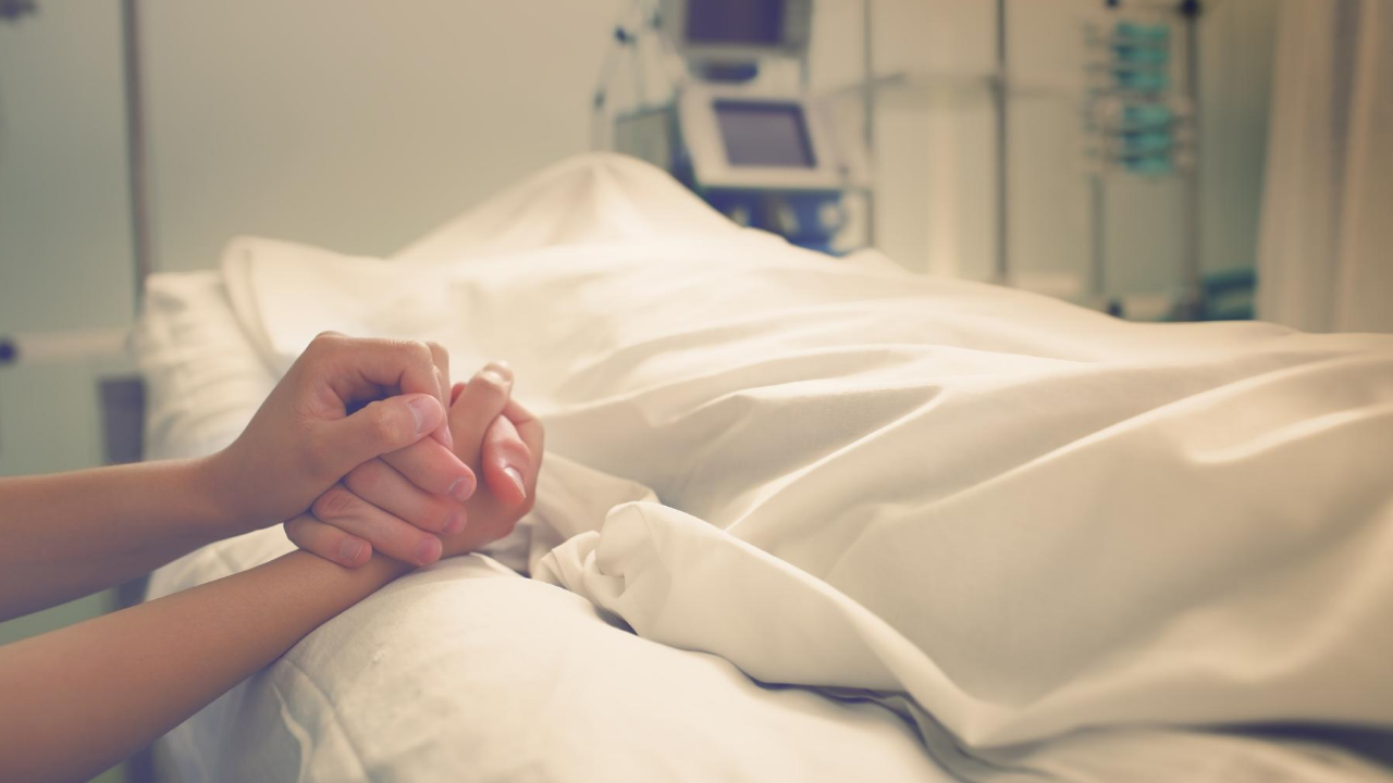 holding hands, one person in hospital bed